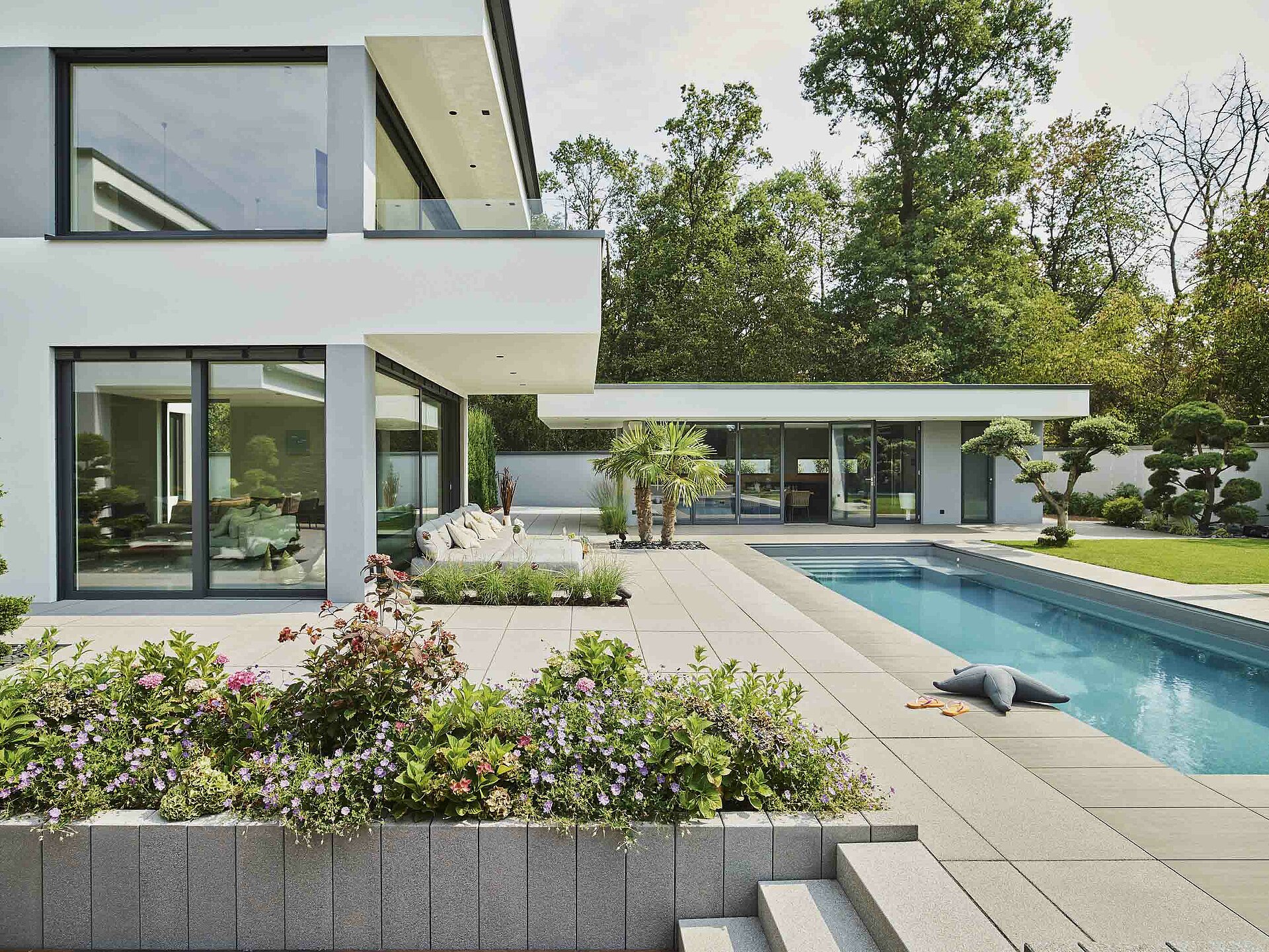 Vario Palisaden aus Beton fassen das Pflanzenbeet ein.