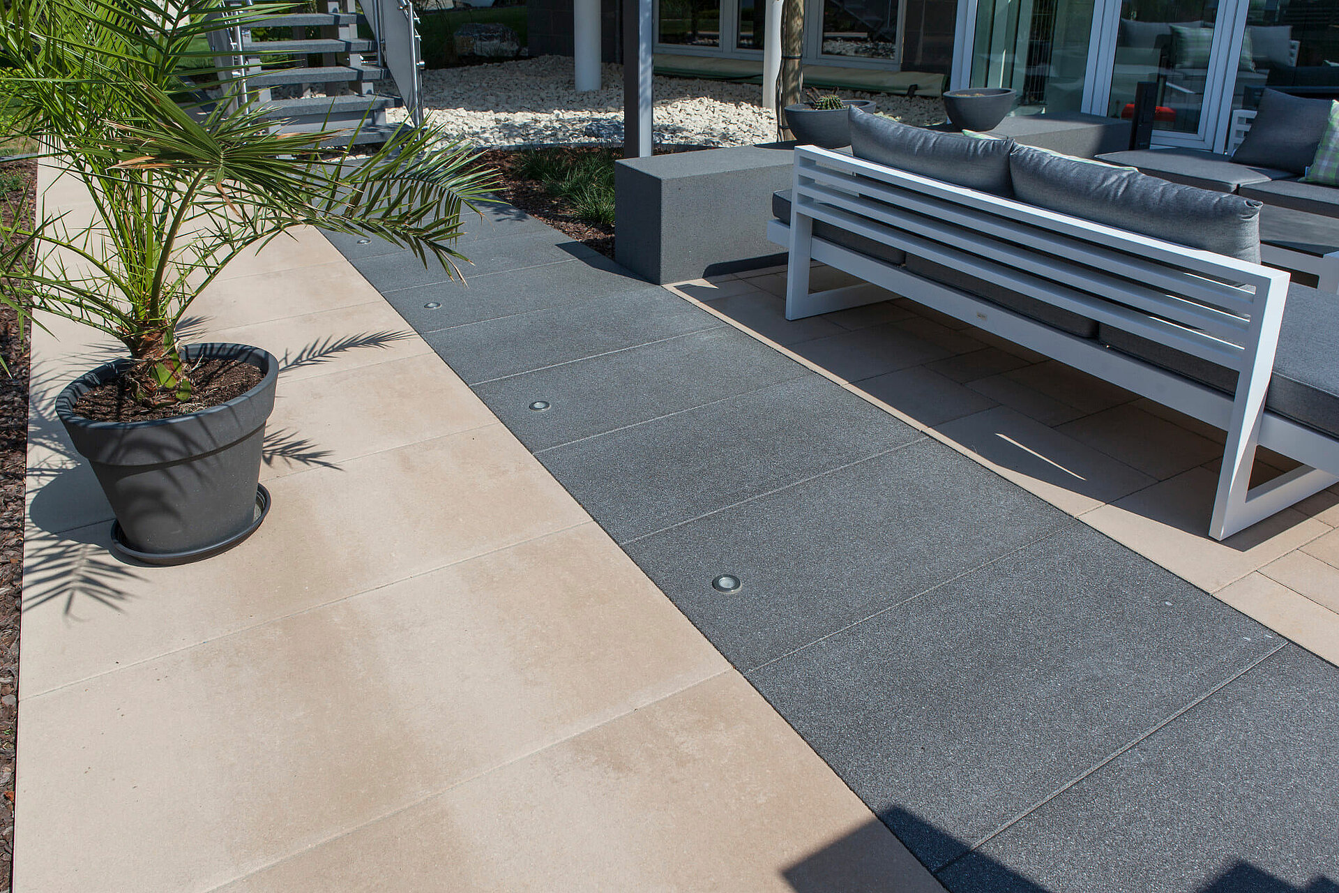 Dunkelgraue Terrassenplatten mit integrierten LED-Lichtern im Garten.