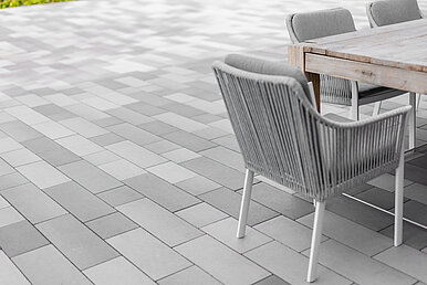 Das Pflaster auf der Terrasse wurde passend zum Mobilar ausgewählt und harmonisiert im hellen Grau.